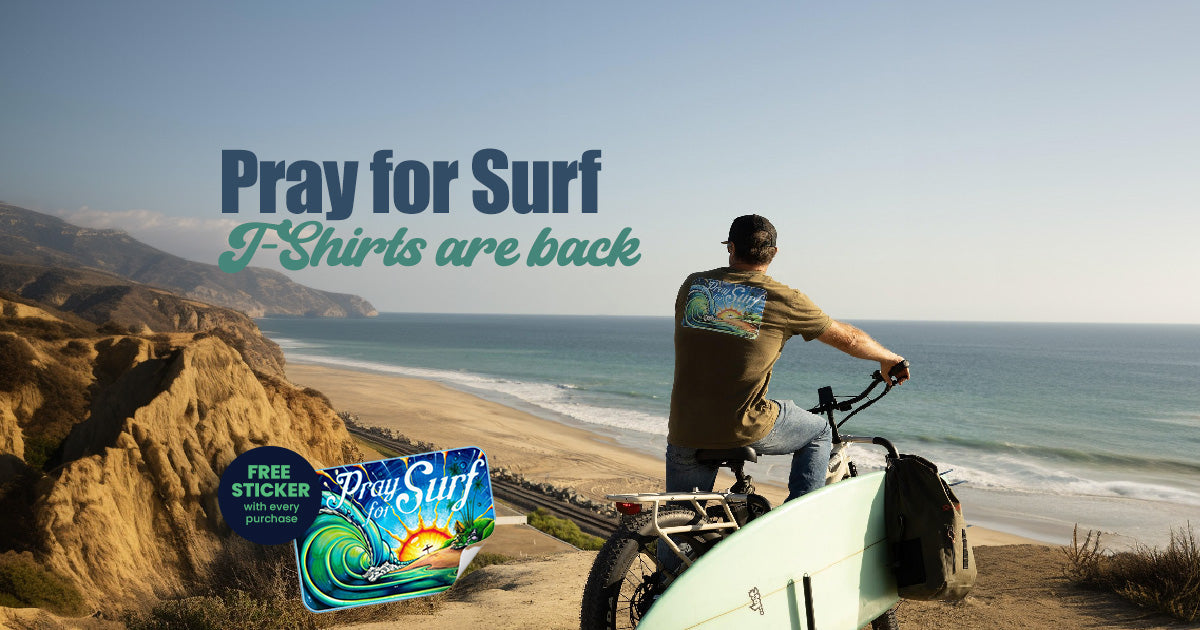 Man on a bike overlooking a beach with 'Pray for Surf' branding.